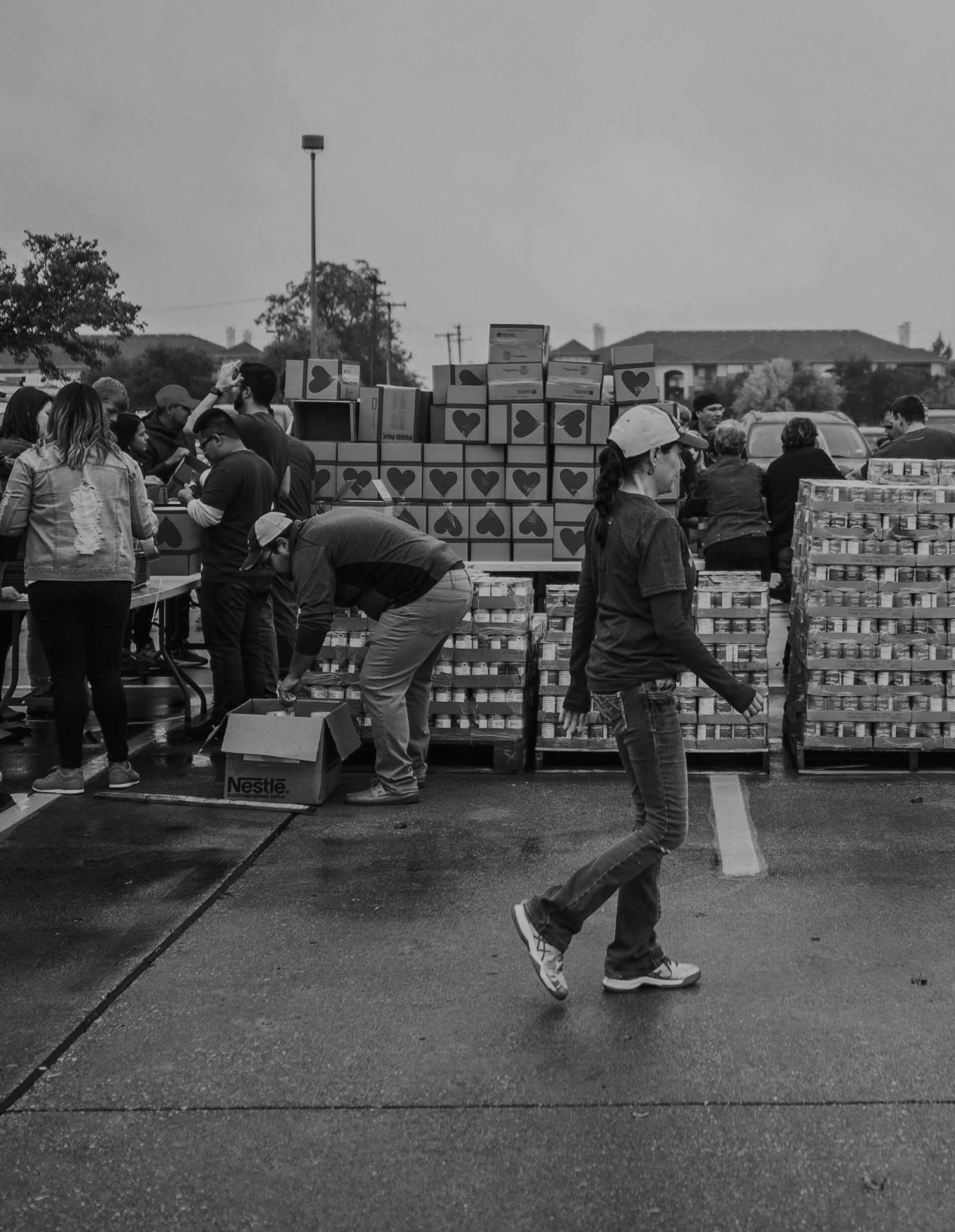 We serve nonprofit organizations in any community. A young woman is walking inside a parking lot with donation boxes.